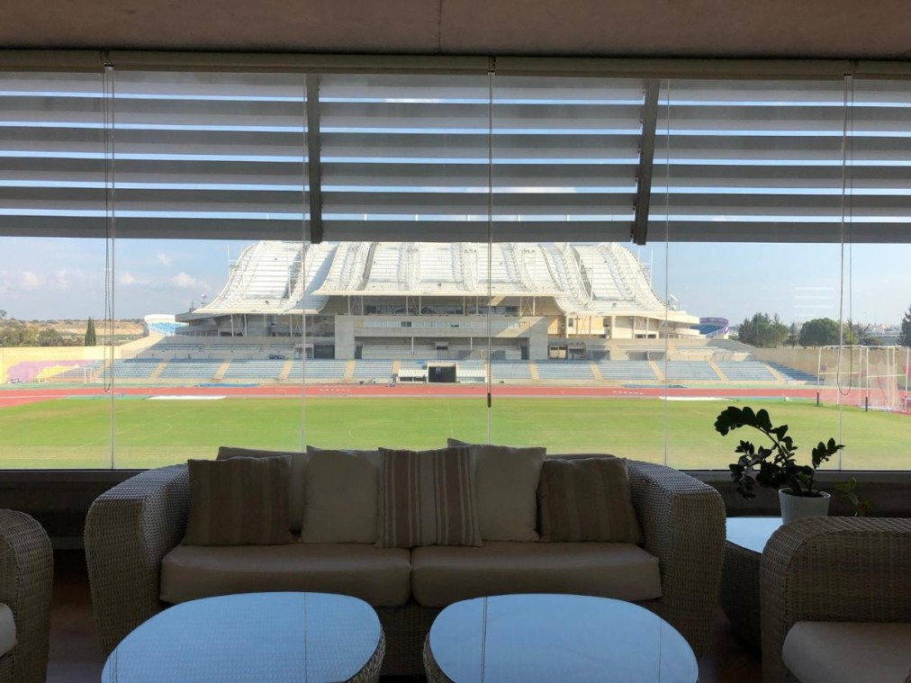 Lounge area with sofas and large window overlooking stadium and running track