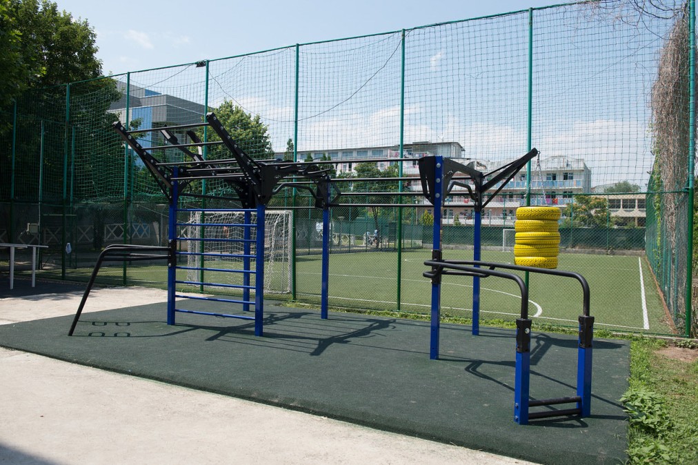Outdoor fitness area with pull-up bars and obstacles, designed for strength drills during training camp