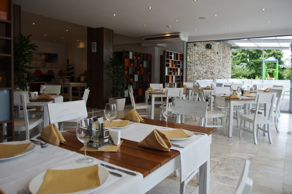 Bright restaurant with white tables, wooden surfaces, and place settings for team meals at training camp