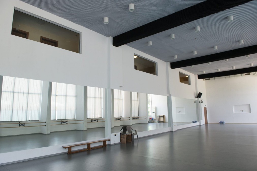 Spacious mirrored studio with benches and natural light, used for coaching and practice sessions
