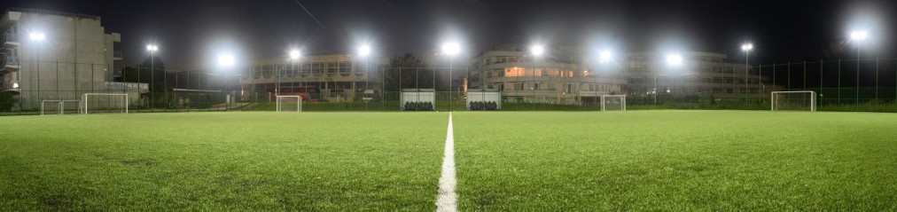 Night view of illuminated soccer field with center line and goals, prepared for evening training camp workouts