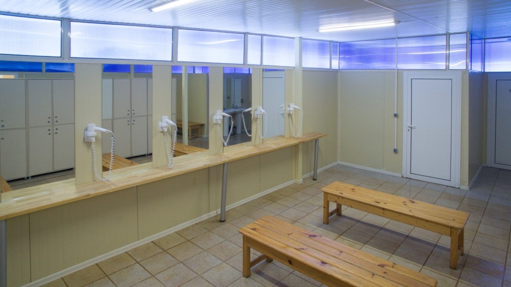 Locker room with benches, mirrors, sinks, and hair dryers for athletes during training camp
