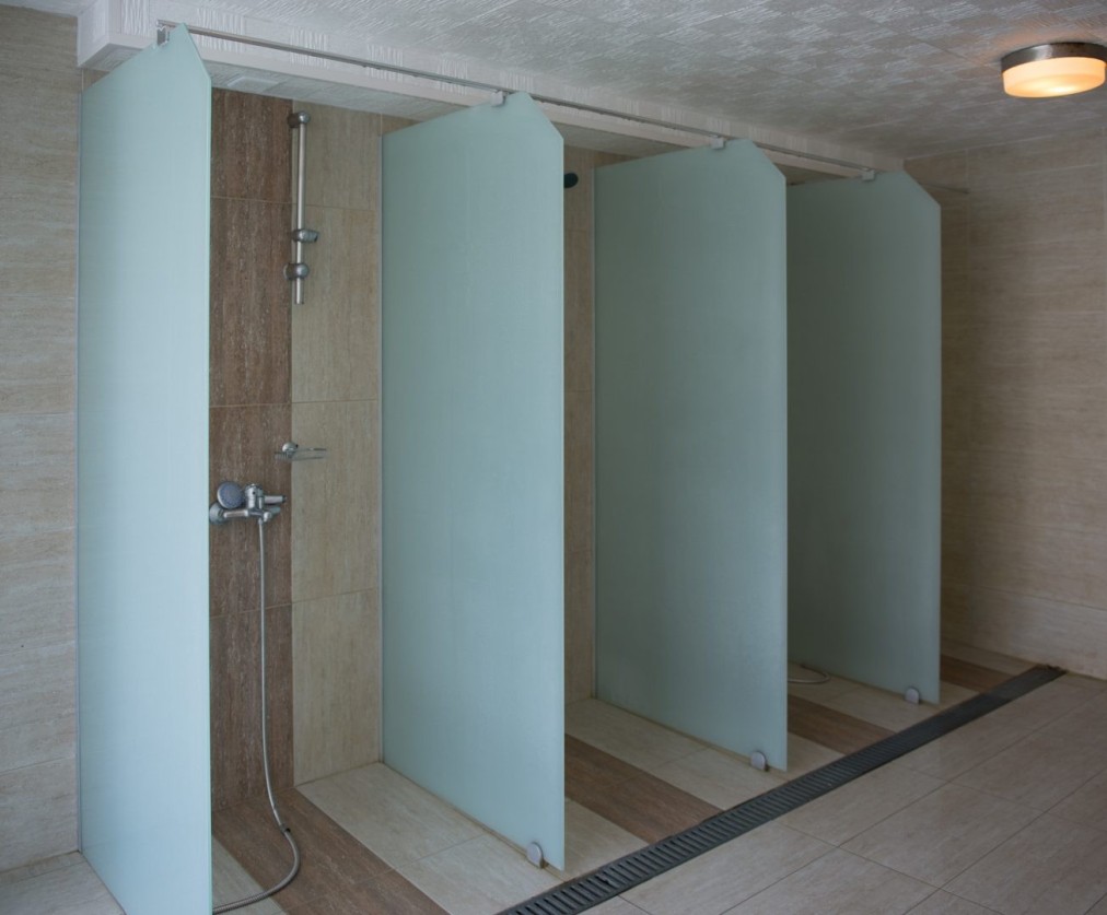 Shower area with individual stalls and frosted partitions for post-workout recovery