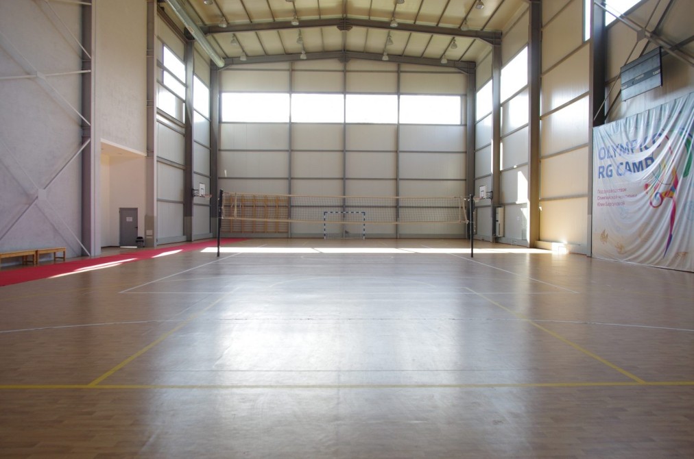 Large indoor sports hall with court markings and high ceiling, set up for team training sessions
