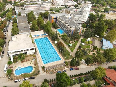 Aerial view of outdoor Olympic swimming pool complex beside hotel buildings, used for training camp swim sessions