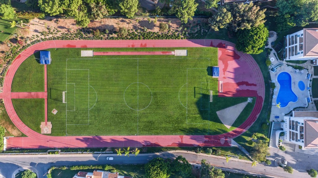 Top-down aerial view of an athletics track surrounding a full-size football pitch.