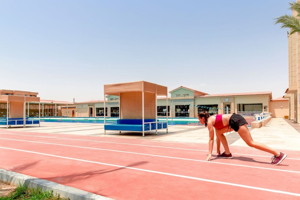 Athlete in starting position on running track near poolside