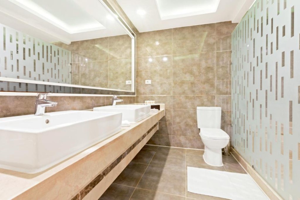 Modern bathroom with large mirror, dual sinks, and glass panel design