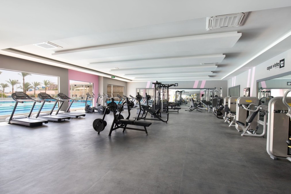 Spacious gym with treadmills, weight machines, and poolside view