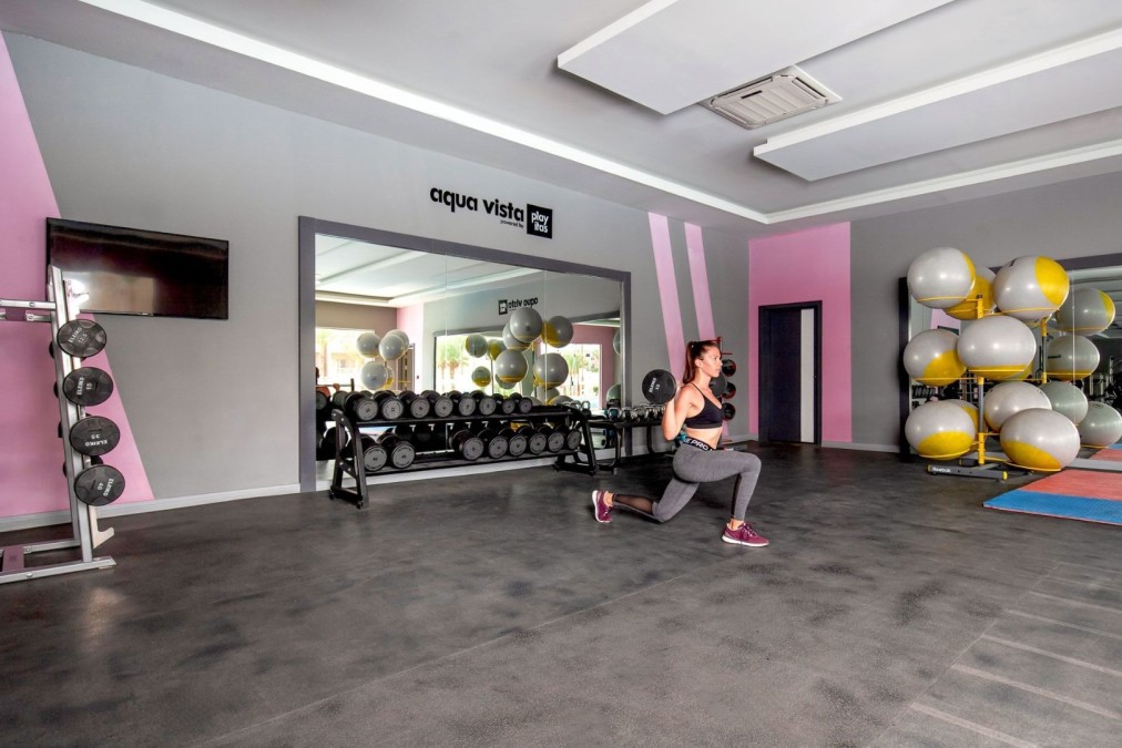 Athlete performing dumbbell lunge in gym with fitness balls and mats