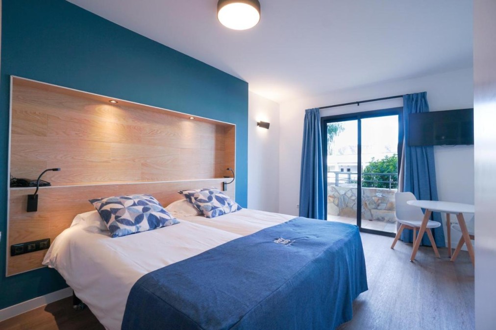 Guest room with double bed, TV, desk, and balcony