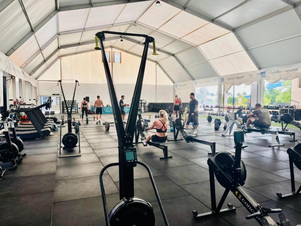 Training tent gym with rowing machines, barbells, and free weights