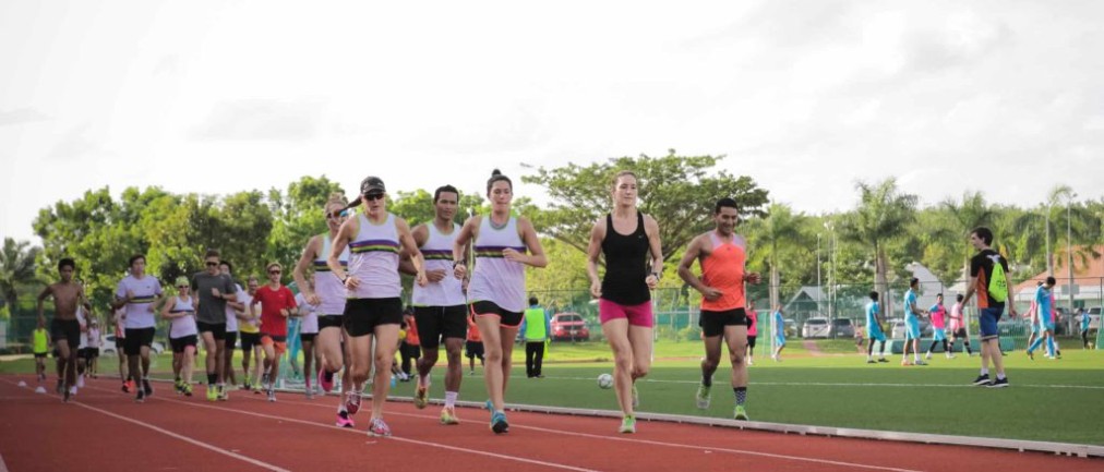 Athletes running on the track, football pitch behind