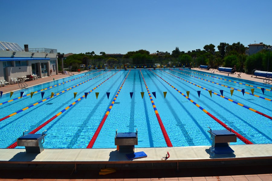 Front view of an outdoor lane pool with starting blocks and training flags.