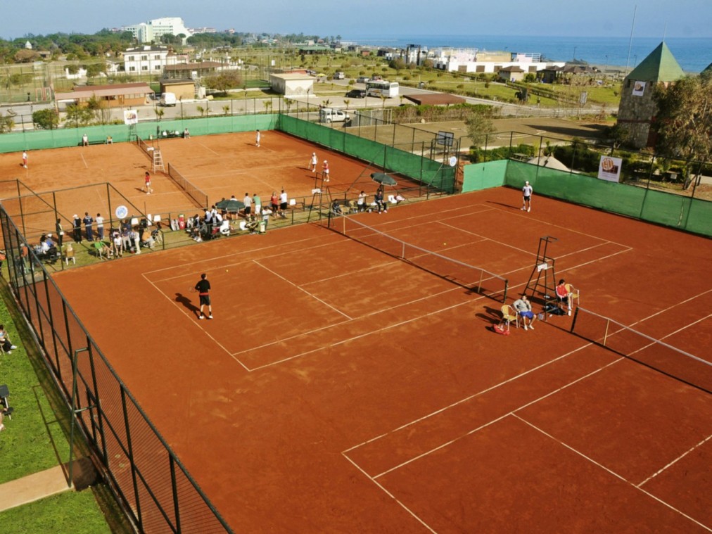 Clay tennis court with spectators watching a match