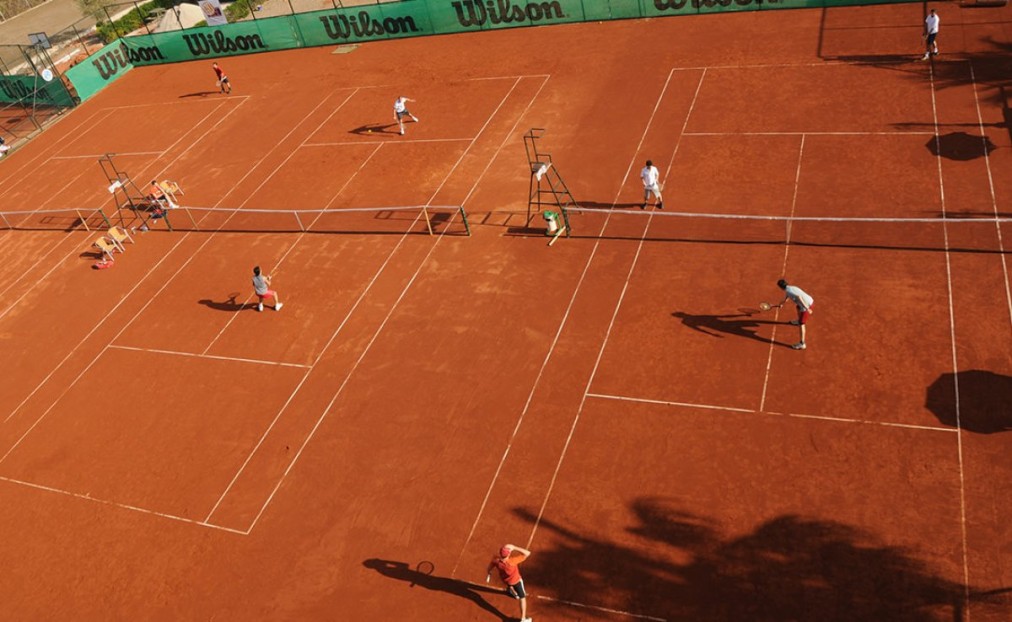 Clay tennis court in play with net and umpire chair