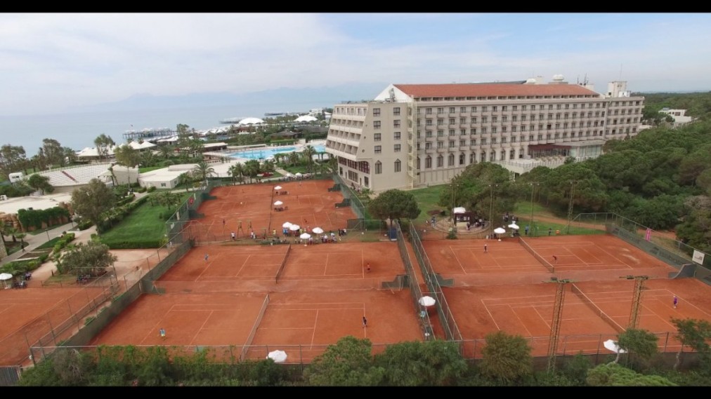 Clay tennis courts by the hotel and sea, aerial view