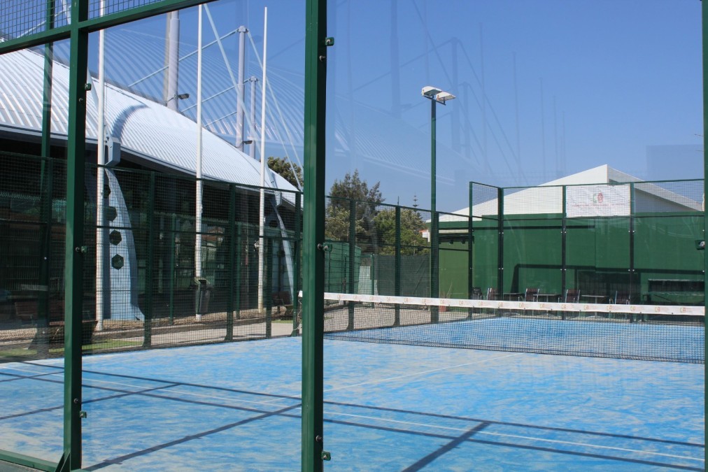 Padel court with glass walls next to the sports building.