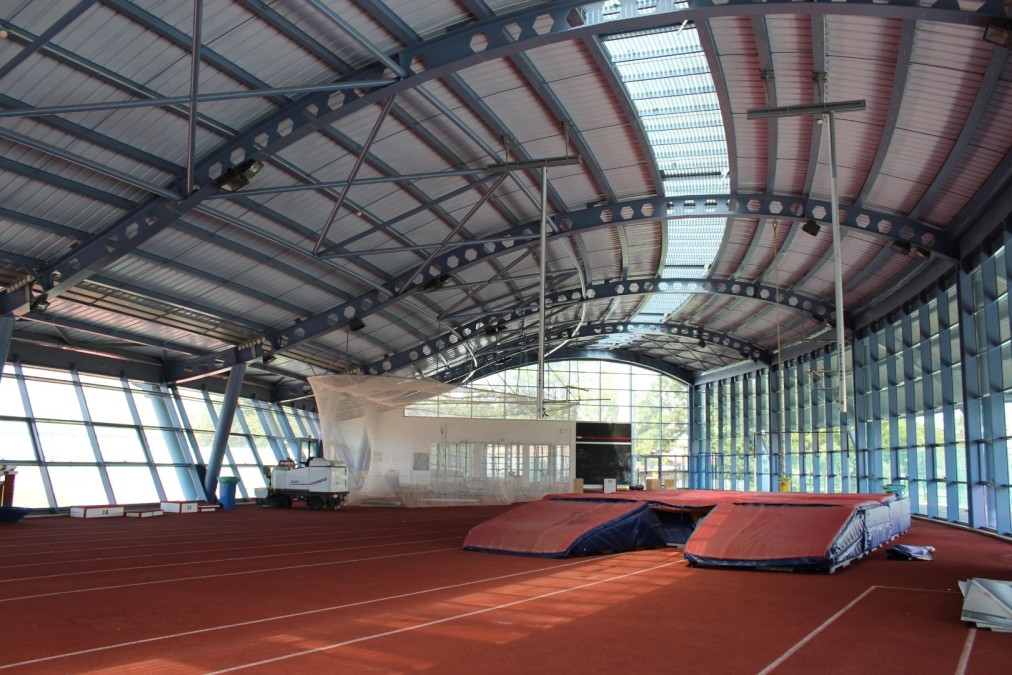 Indoor athletics hall with lanes and pole vault mats.