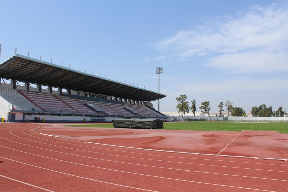 Outdoor stadium stand beside a running track and grass field.