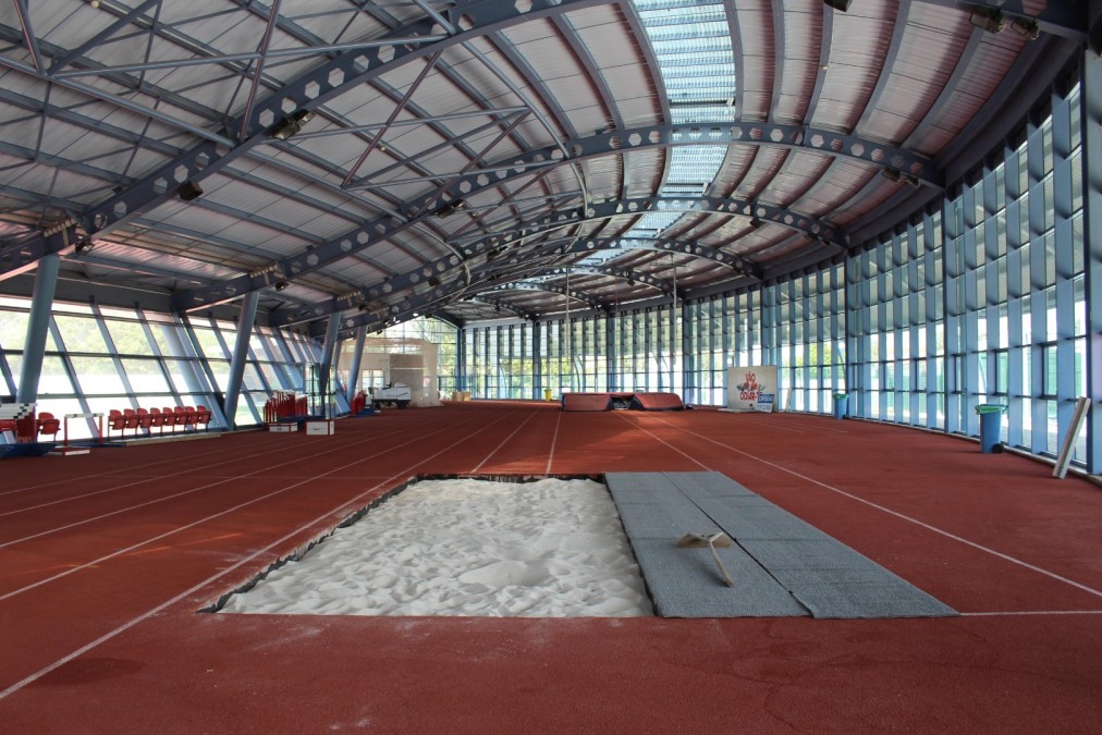 Indoor athletics hall with running lanes and a sand pit.
