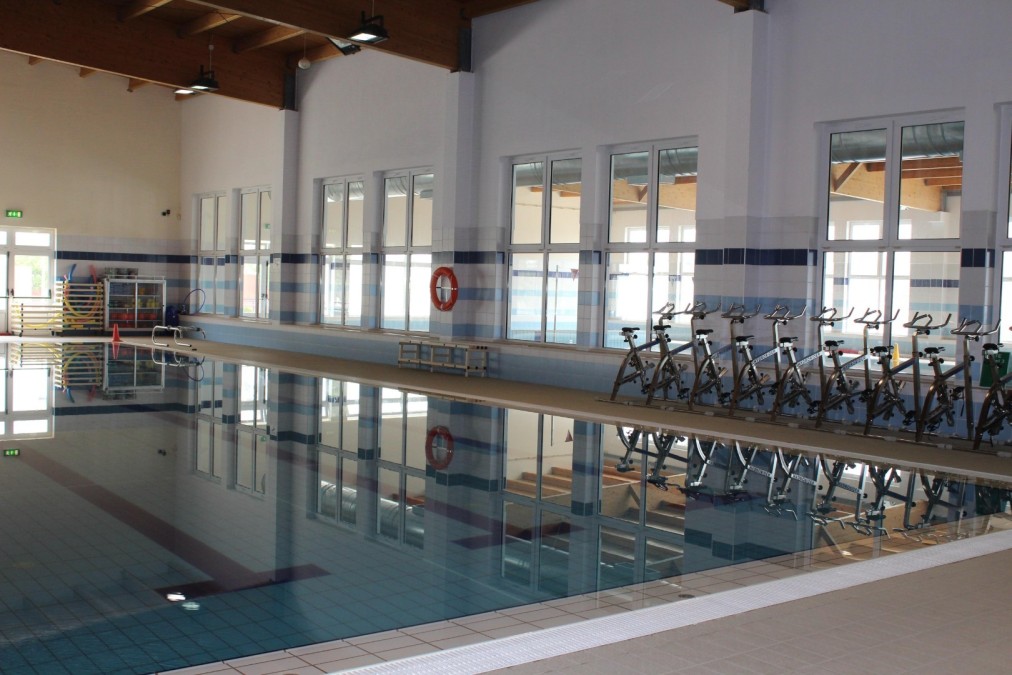 Indoor swimming pool with aqua bikes along the pool deck.