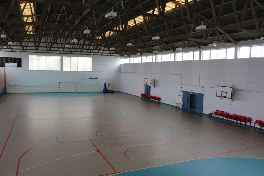 Indoor sports hall with court markings, hoops and a handball goal.