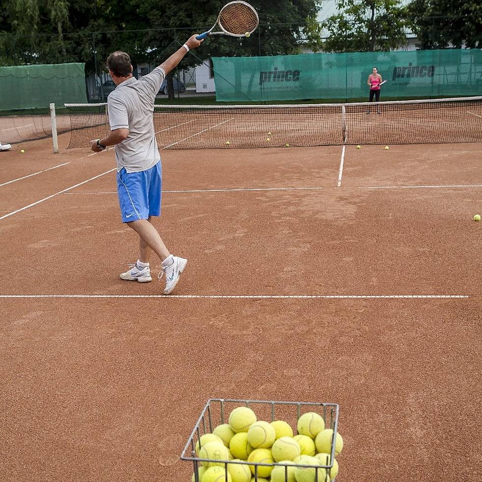Clay tennis court with coach and ball basket