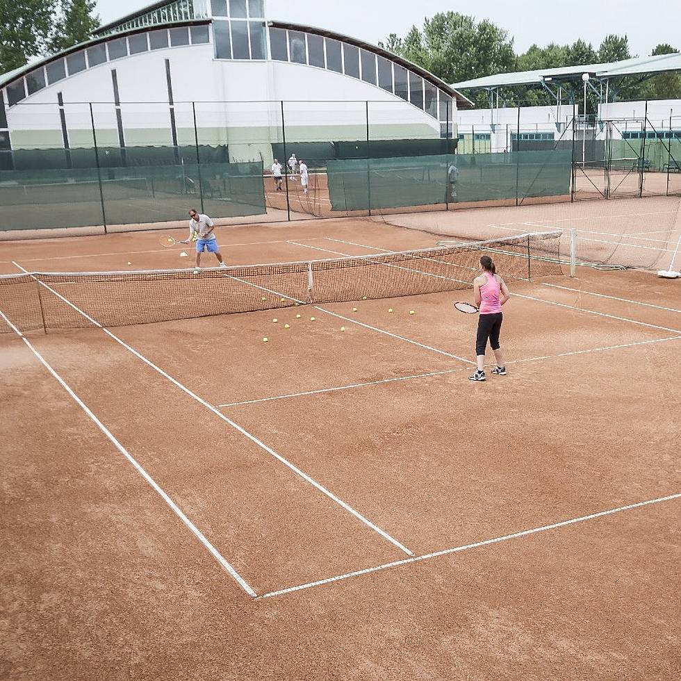 Clay tennis courts with players training