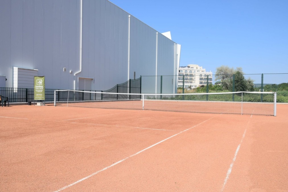Clay tennis court beside indoor hall