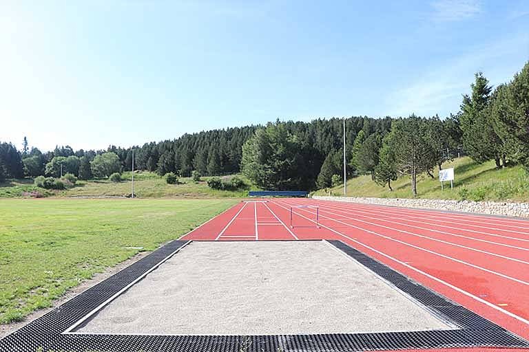 Long jump pit with hurdles on the track