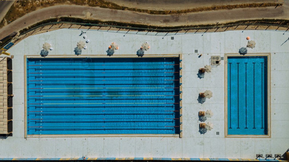 Aerial view of two outdoor swimming pools with lanes and umbrellas