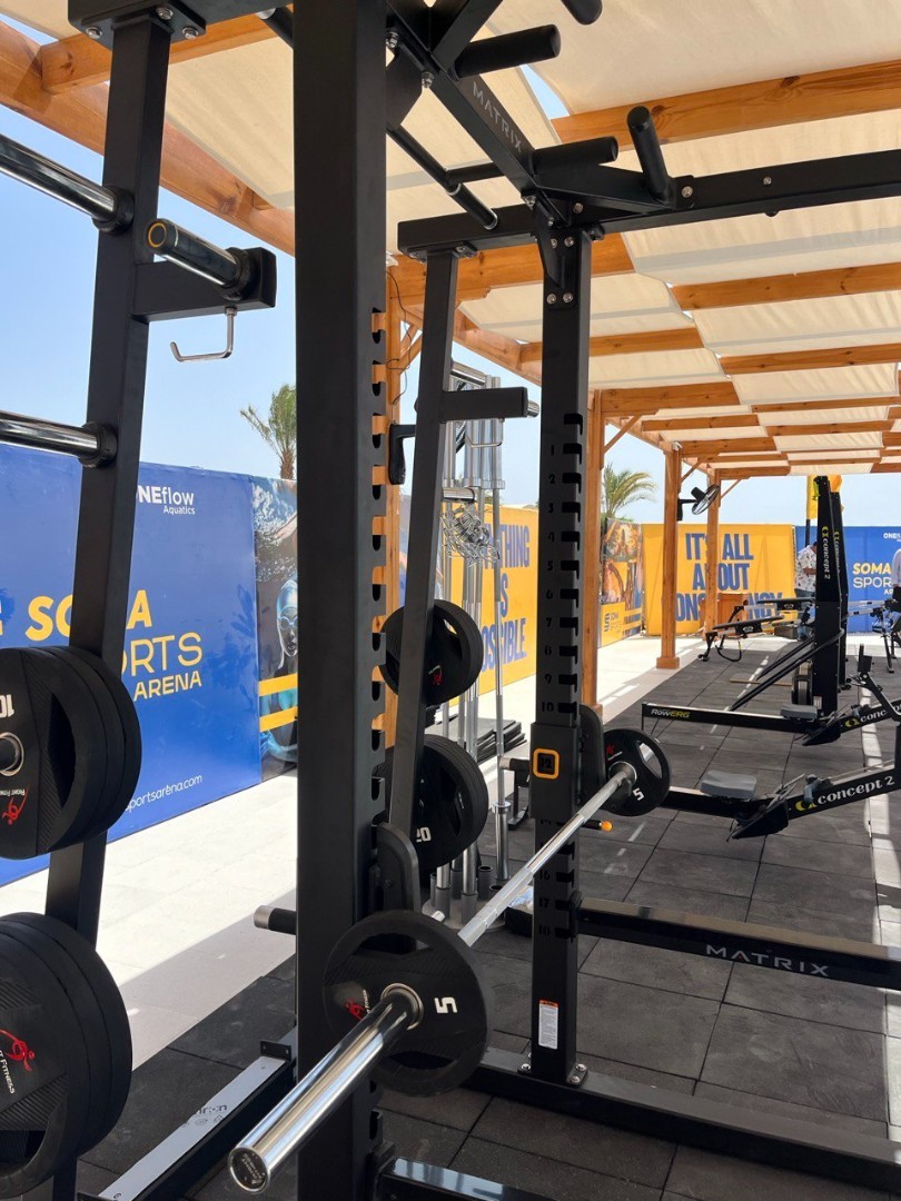 Outdoor gym area — squat racks and barbells under a covered structure