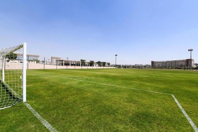 Green football field with white goalposts and boundary lines, used for team training sessions and practice drills