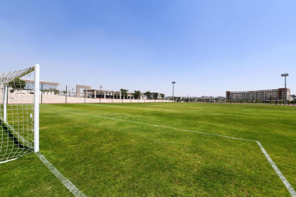 Green football field with white goalposts and boundary lines, used for team training sessions and practice drills