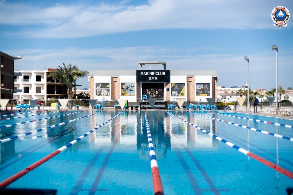 Olympic-size swimming pool with lane dividers in front of Marine Club Gym