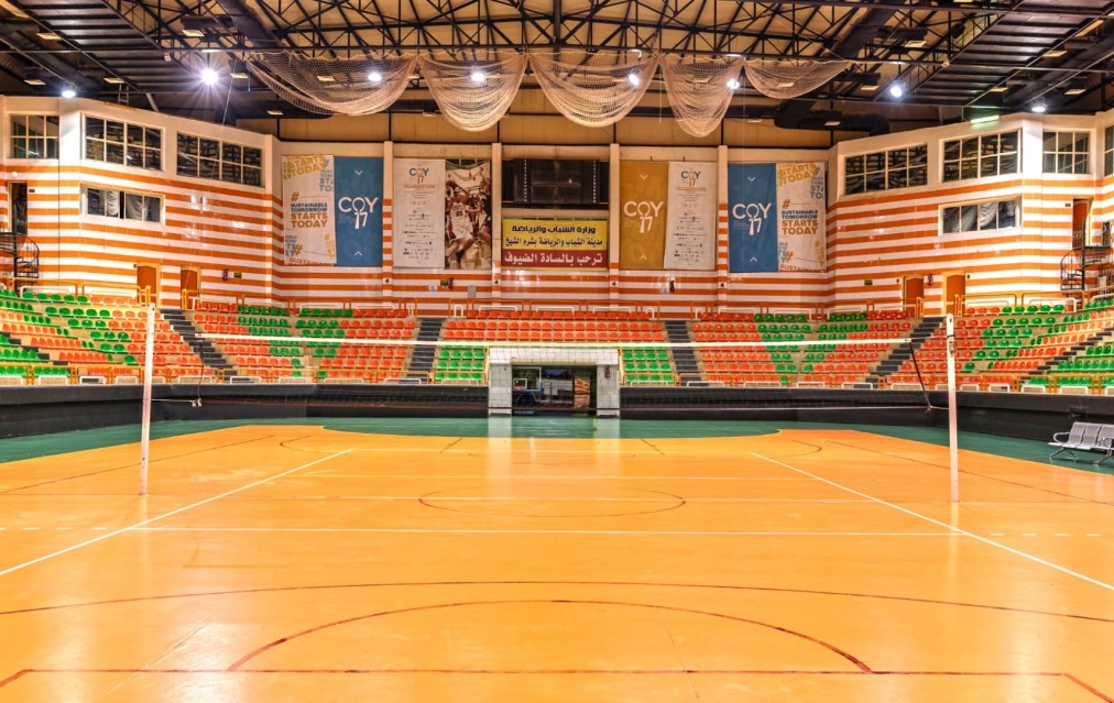 Volleyball court with net posts, tiered seating and event banners on walls