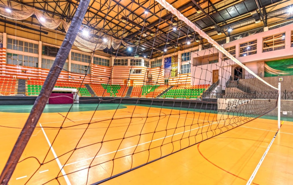 Volleyball net at court level with playing surface and spectator tribune behind