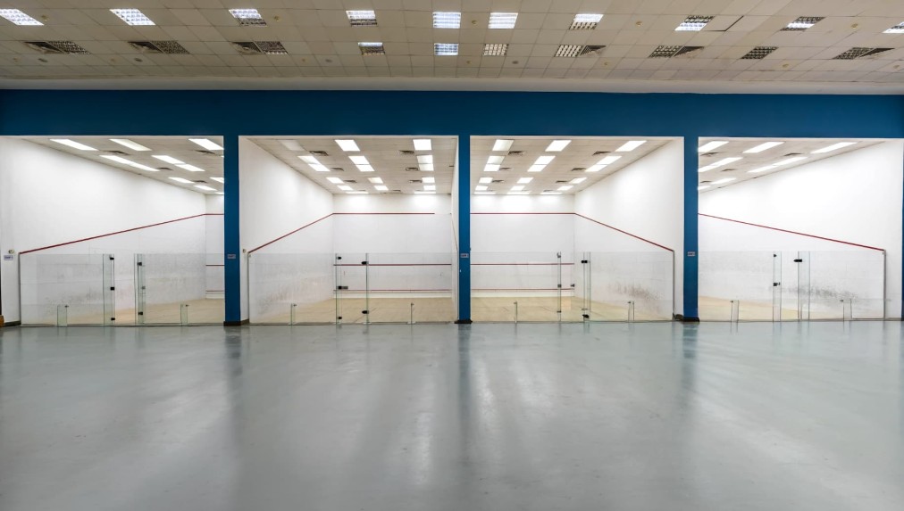 4 indoor squash courts with glass back walls, wooden floors and overhead lighting