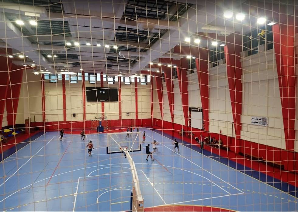 Indoor multipurpose sports hall with a volleyball net set up on a marked court.