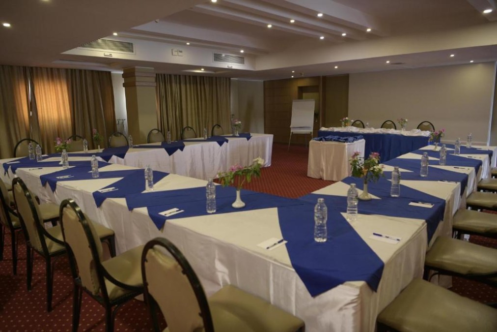 Conference room with U-shaped tables, water bottles, and flip chart.