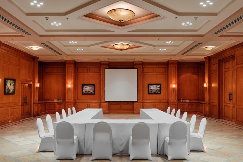 Wood-paneled meeting room with U-shaped tables and projector screen for training camp team briefing