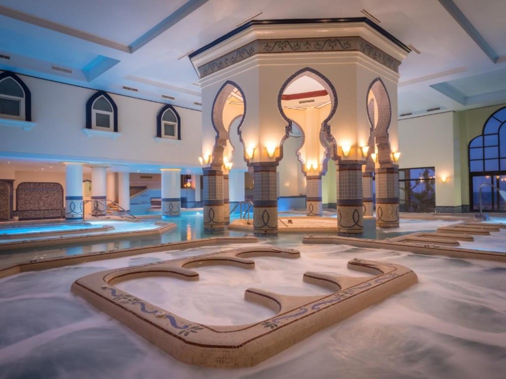 Indoor jacuzzi/thalasso area with foamy water and dramatic arches, relaxing recovery environment
