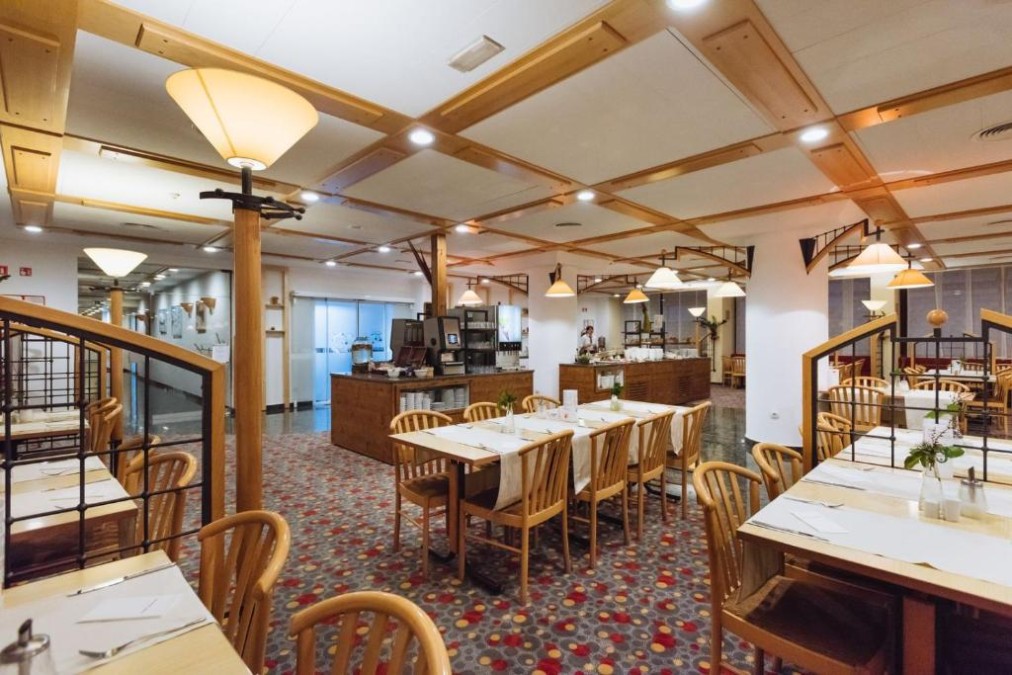 Restaurant dining area with set tables, buffet counter, and warm ambient lighting.
