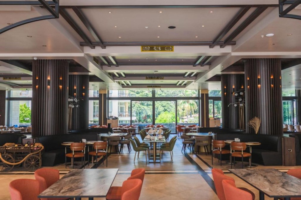Spacious modern restaurant with large windows, central communal tables, and mixed seating areas.