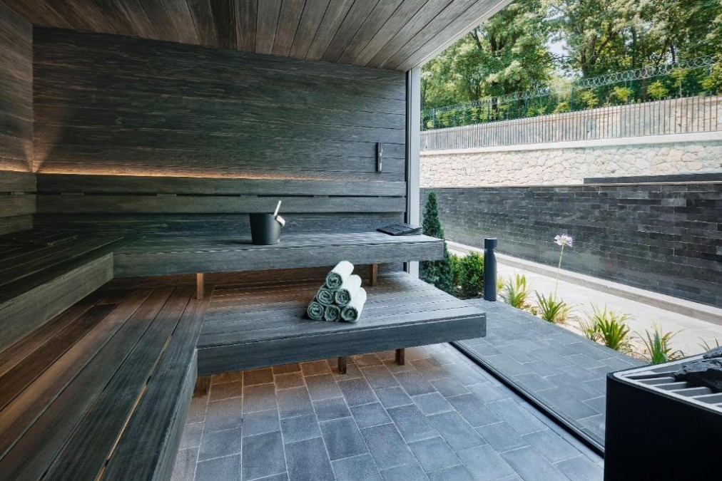 Modern sauna with dark wood benches and towels by a large window.