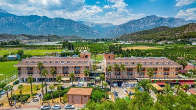 Exterior view of the hotel building with palm trees and mountains in the background.
