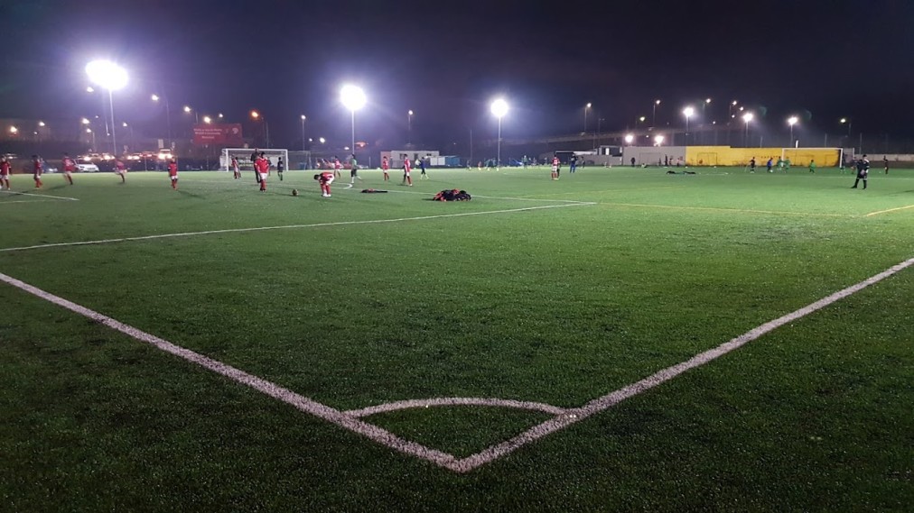 Floodlit artificial turf football pitch during an evening training session.