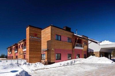 Snow-covered hotel exterior with timber cladding under clear winter sky.