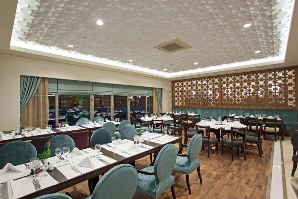 Indoor restaurant dining room with set tables and upholstered chairs.